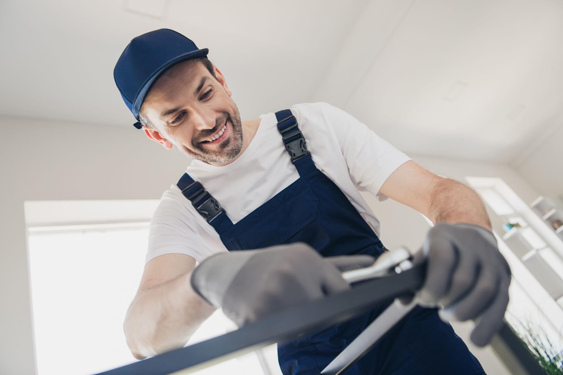 Fröhlicher gutaussehender Handwerker, der an der Renovierung von Häusern mit Werkzeugen in einem hellen Raum arbeitet